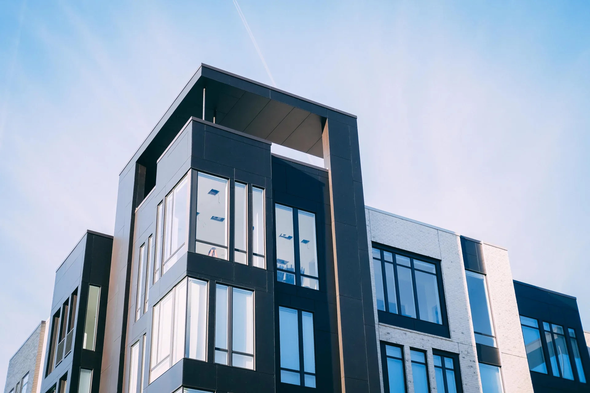 Modernes Wohngebäude mit dunkler Fassade und großen Fenstern von unten fotografiert